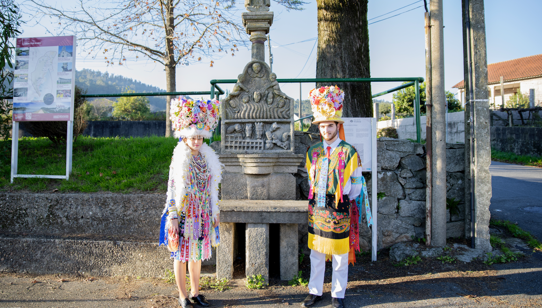 Una Madama y un Galán posan delante de la la fuente en Vilaboa. 